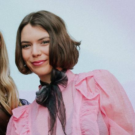 Girl in pink blouse and black scarf smiling at camera