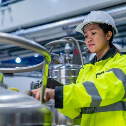 Woman in safety PPE in front of a vat.