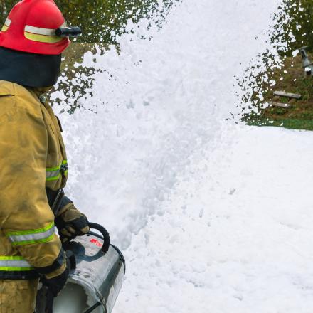 Stock picture of a firefighter in protective clothing extinguishing a fire by feeding foam. 