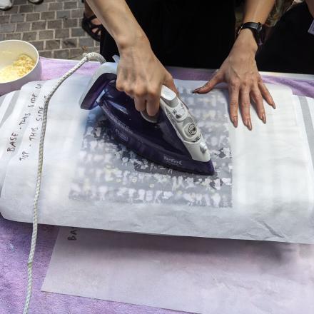A person ironing a piece of fabric covered in beeswax