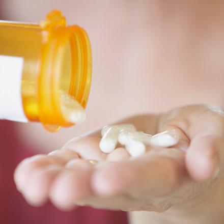 Closeup of woman pouring tablets out of a bottle and into her hand