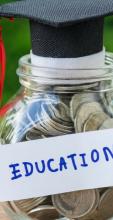 Glass container filled with coins with a mortarboard at the top. Container labelled education