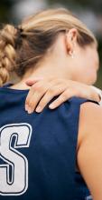 A netballer grimacing while they hold their shoulder