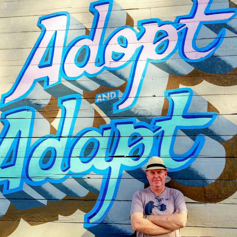 Dr Brent Jacobs standing in front of 'Adopt and Adapt' artwork (photo supplied by Brent Jacobs)