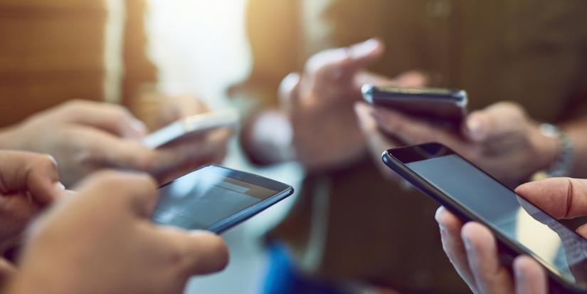 Close shot of four people in a circle using mobile phones