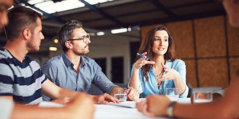 Three people talking in a team meeting in an office