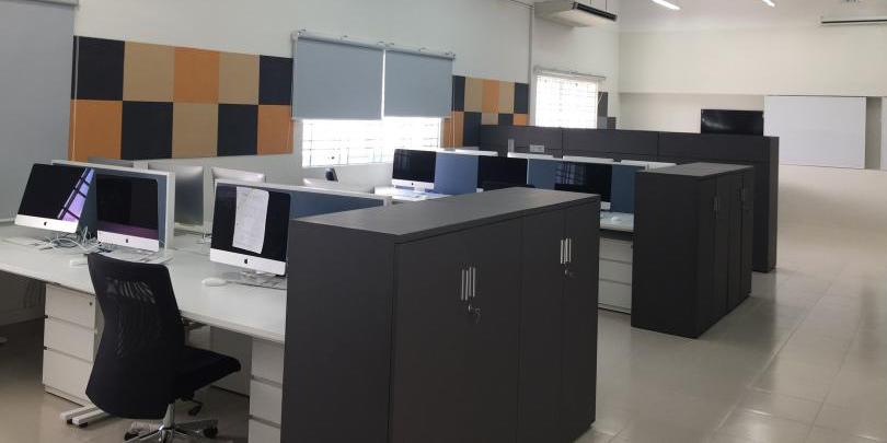 A room is filled with open plan seating and desks, with brightly coloured panels on the wall