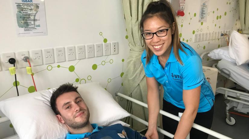 Female physiotherapy student treating male patient in hospital bed