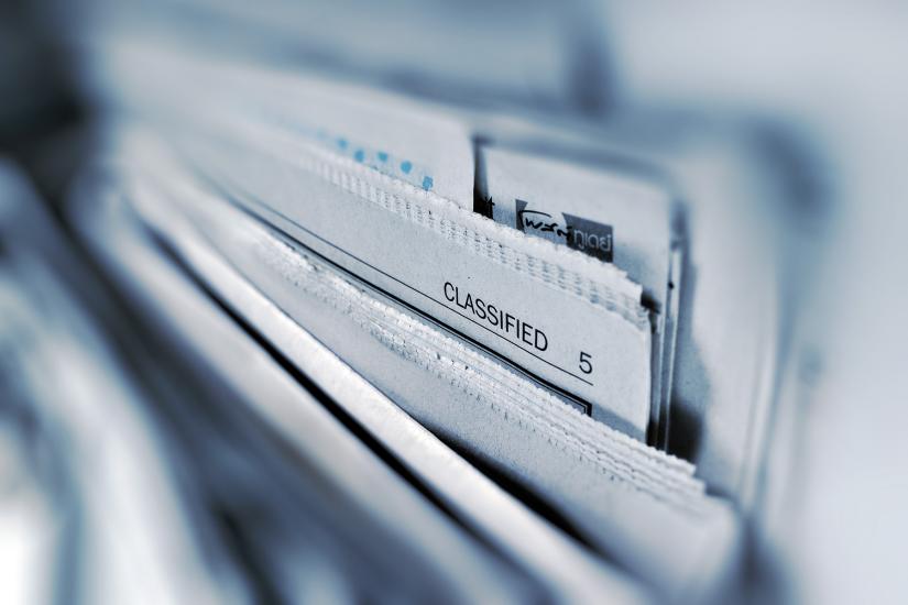 A stack of newspapers, with the header of one visible. It reads 'classified'