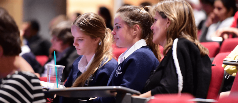 Two female high school students in uniform sitting with their Mother