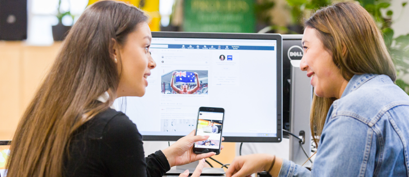 Two students looking at a phone and computer screen