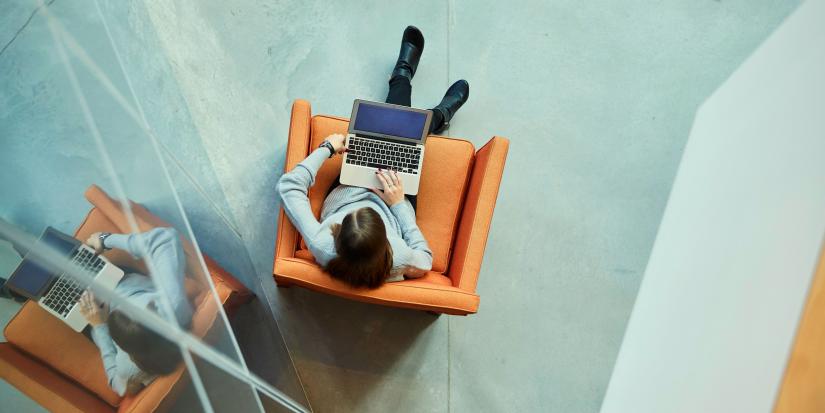 Overhead view of a female student on her laptop and her reflection in nearby glass