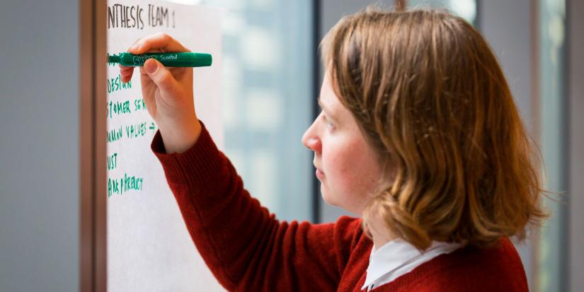 A woman writing a list on a large piece of paper in a team workshop