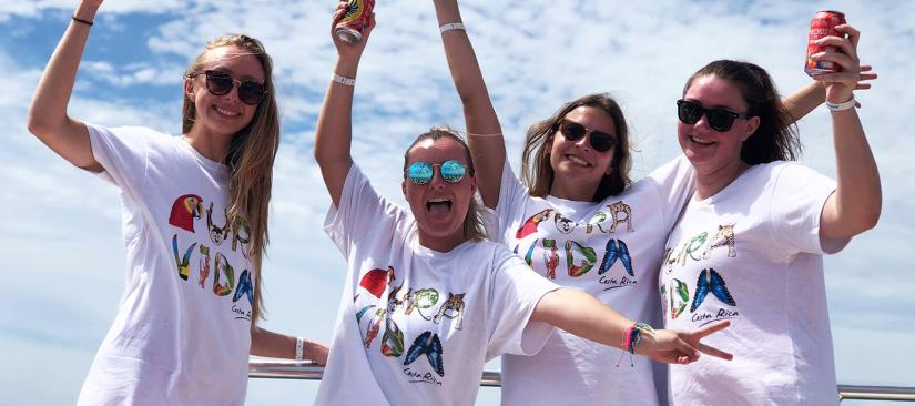 Four happy women in their matching tshirts with their arms in the air