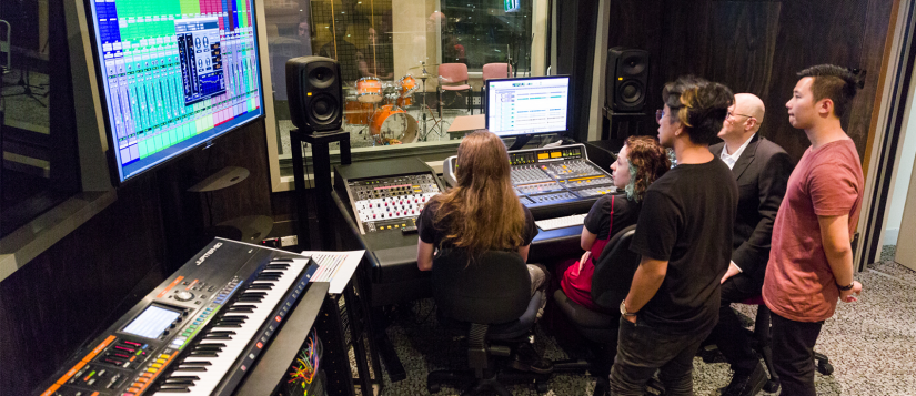 A group of students recording music in a sound booth