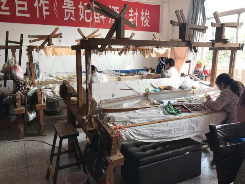 Kesi workshop with people using weaving looms to cut silk