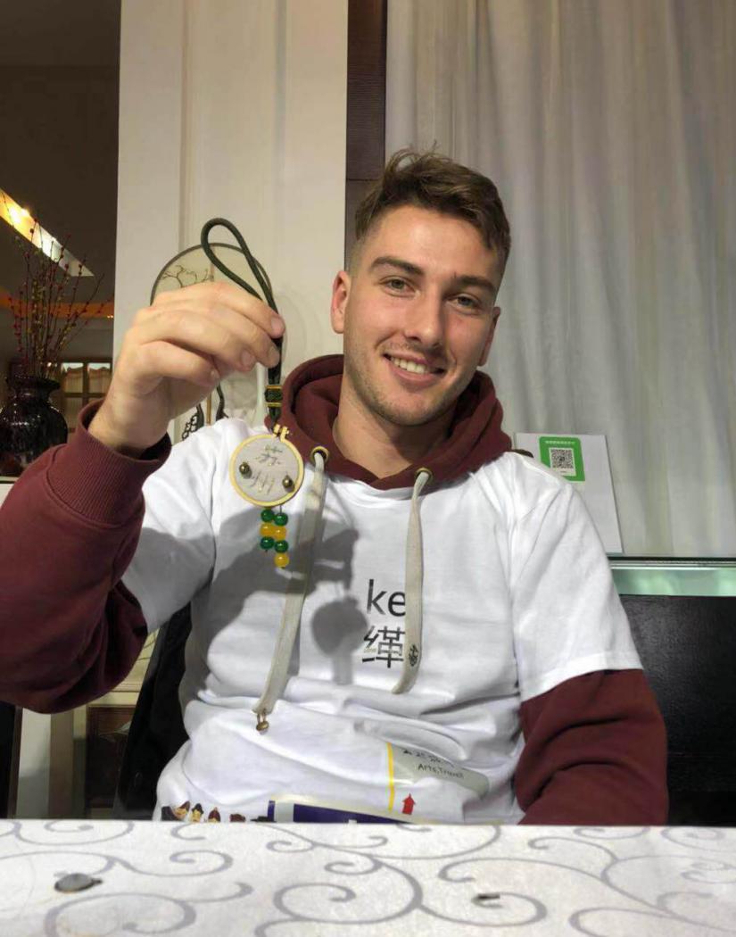 Morgan smiling and holding up a piece of beaded art he constructed 