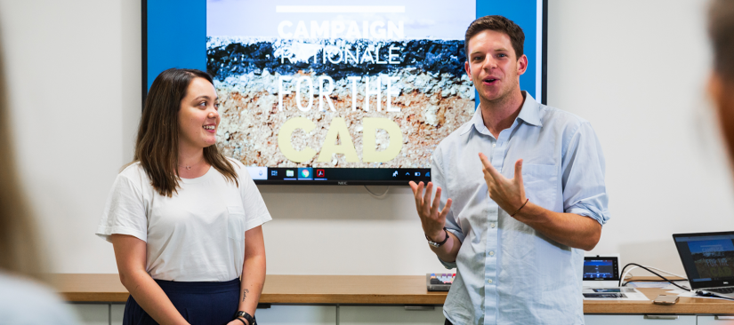 Two students pitching in front of a presentation