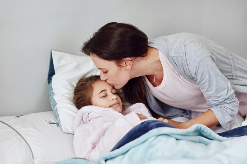 A parent putting their child to bed