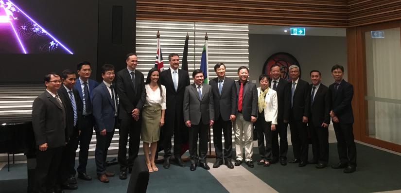 A group of people smile in front of two flags