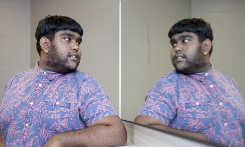 Dashie Prasad looking towards a bathroom mirror