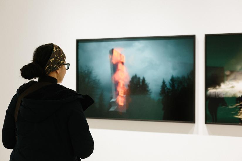 Student viewing photographic pieces on a gallery wall