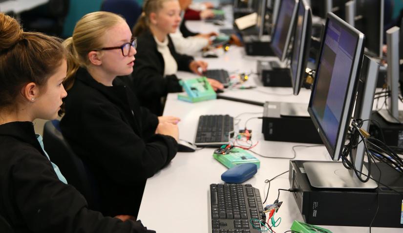 3 girls on computers with electronic boards and speakers