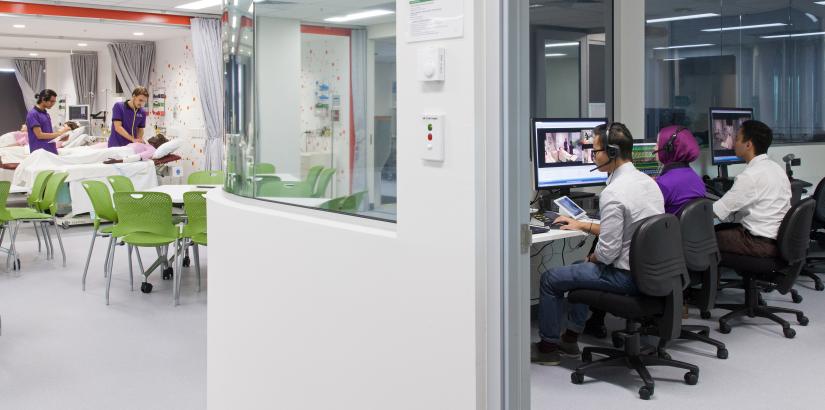 3 UTS supervisors in a control room supervising students in a laboratory.