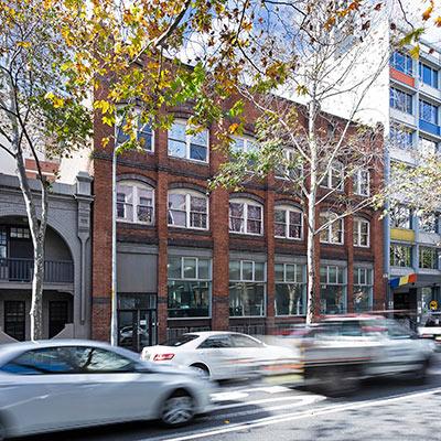 Red-brick exterior of Building 16 with busy Harris St in foreground