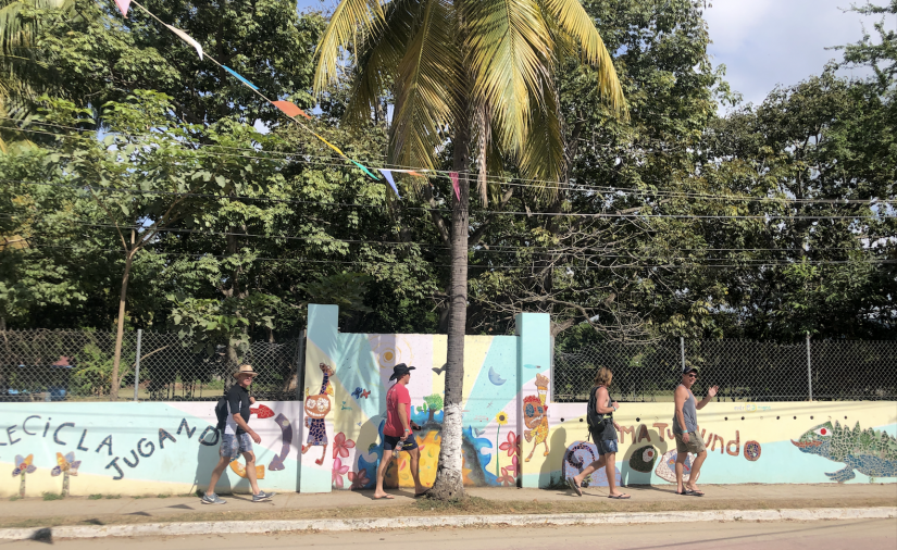 A group of men walking past a colourful wall