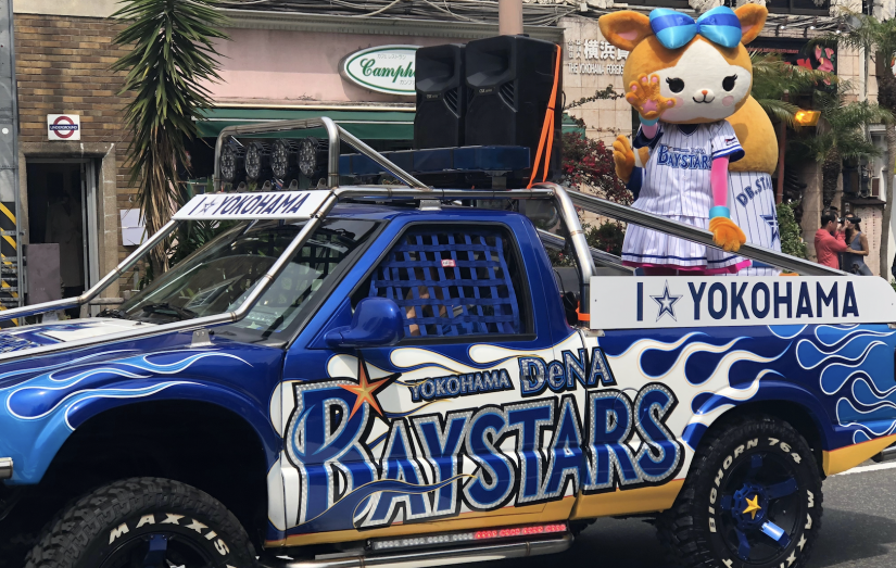 A Japanese Yokohama mascot waving from a truck