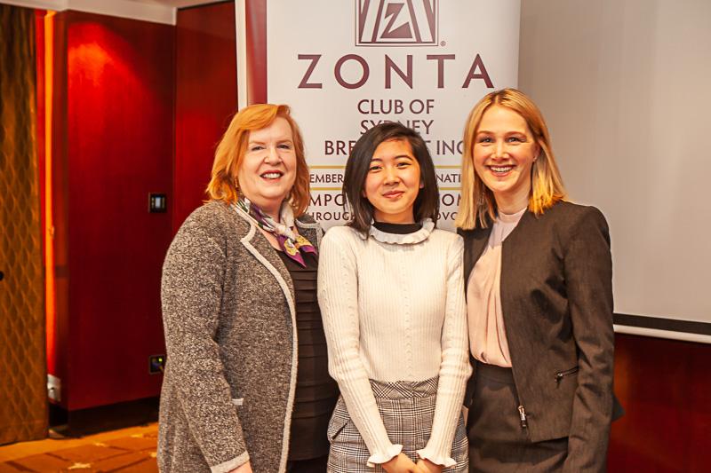 Three women in front of Zonta banner