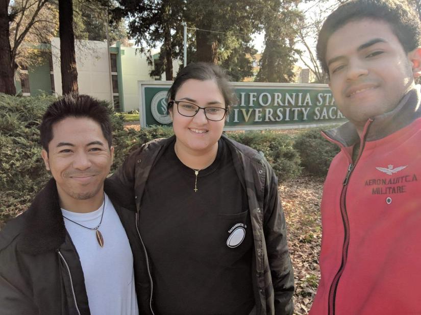 Danielle and two friends standing in front of a college sign