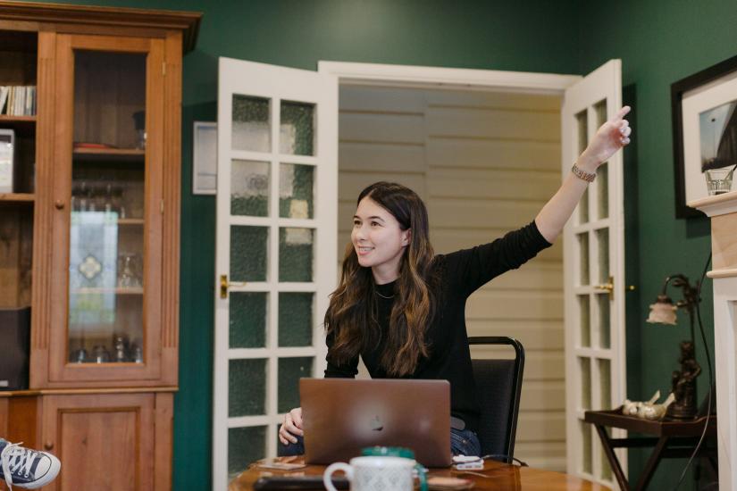 Janine with a laptop in a meeting, pointing to something