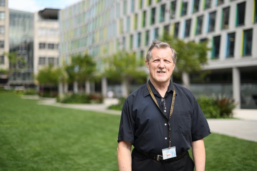 Garry Irwin standing on the Alumni Green in front of Building 7