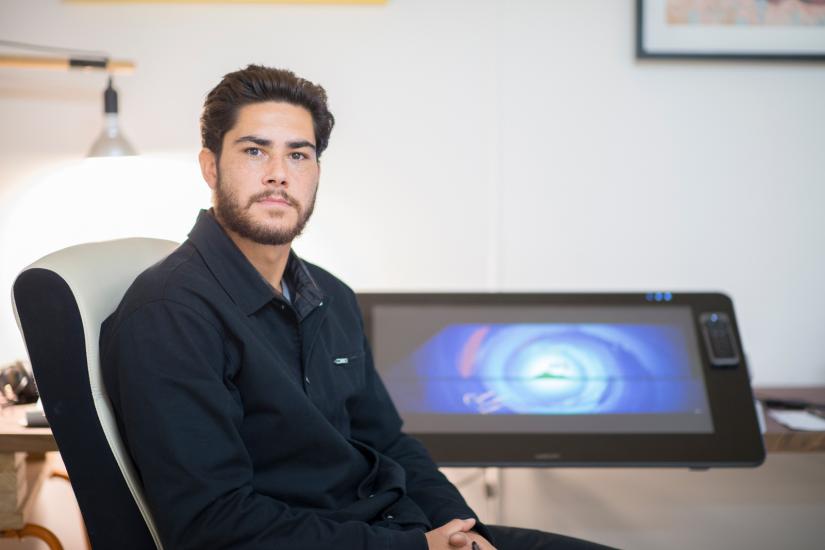 Jake Duczynski sitting on a chair in front of a drawing tablet