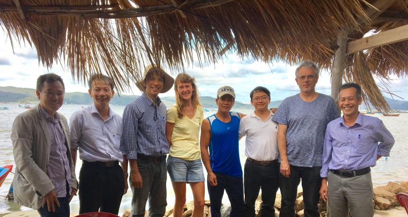 A group of people pose in front of a bay