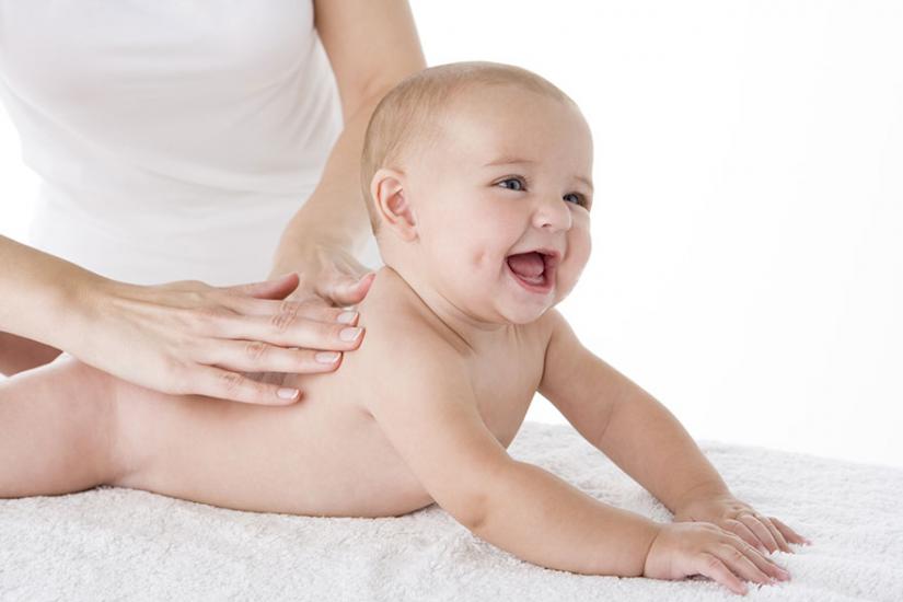 Baby on tummy being rubbed by woman's hands