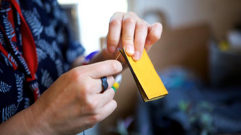 A piece of yellow leather being sewn. Close-up.