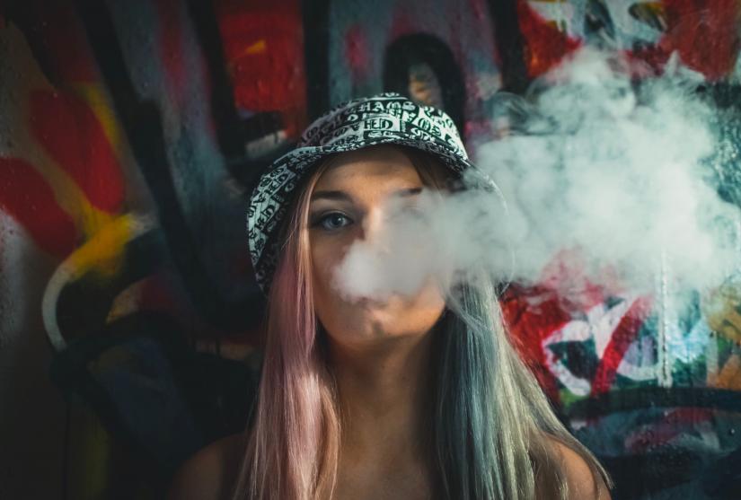 A young woman partially obscured by a cloud of tobacco smoke