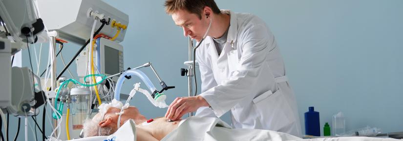 A doctor stands over a patient on a ventilator in hospital.