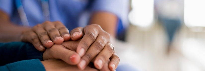 A nurse places hands on a patient's to comfort them