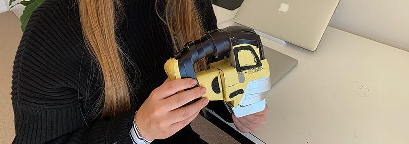 young woman holding crafted model of a hand mixer