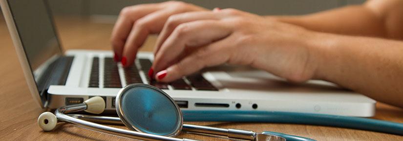 Person working on laptop with stethoscope