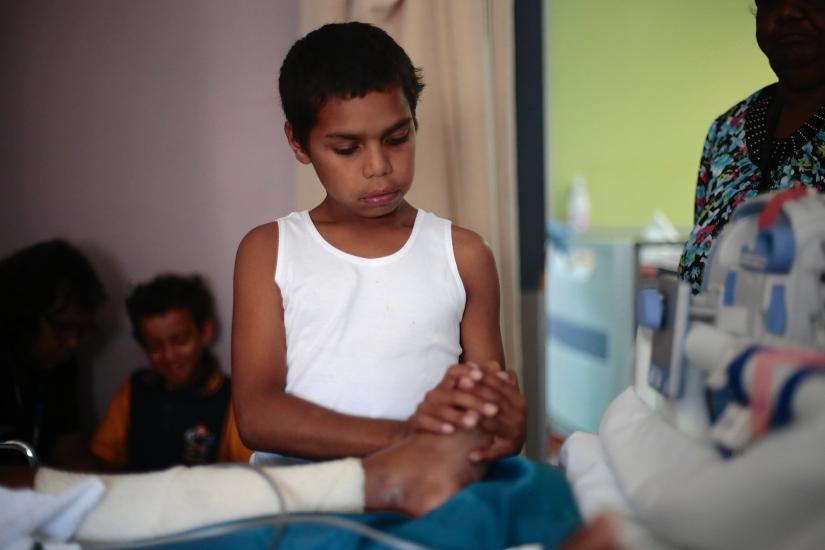 Dujuan Hoosan rubbing his grandmother's foot as she lies on a hospital bed