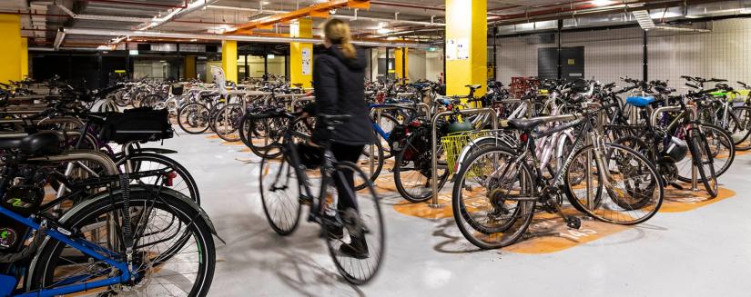 A person walking a bike into a room full of bikes