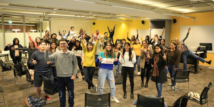 Group people with arms up in classroom setting