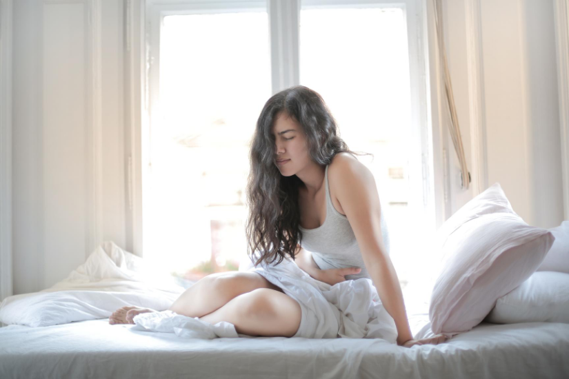 A woman holds her stomach in pain