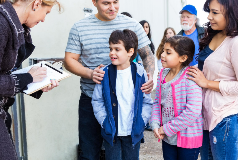 A family is surveyed by a public health officer on the street