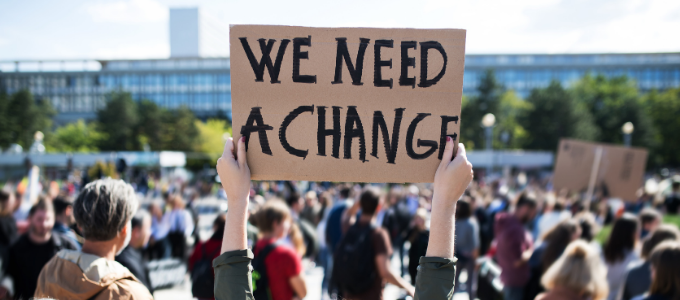 A protester holds a sign reading 'We need a change'